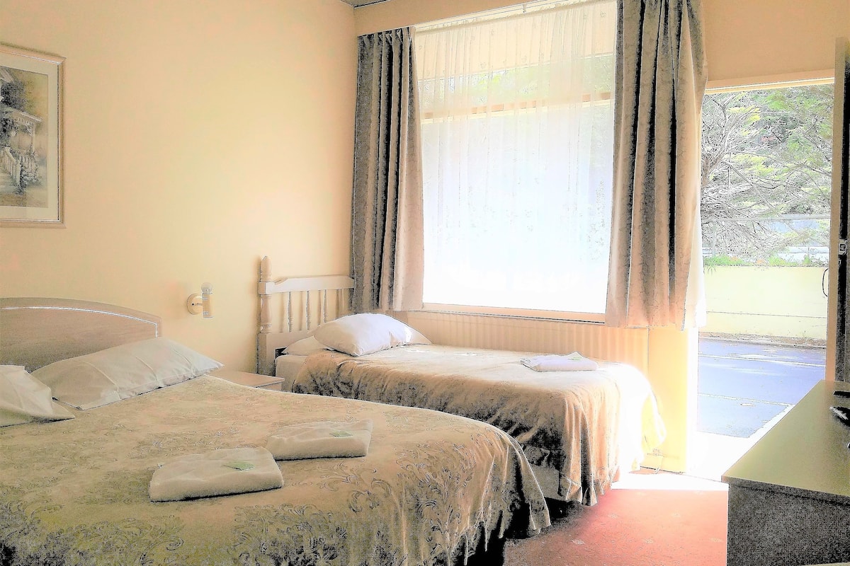 A room with two beds, a desk, and a window with curtains.