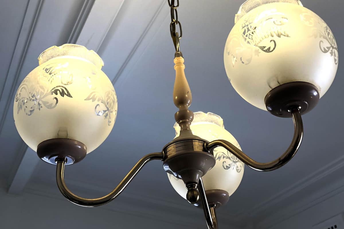 A chandelier with three white lampshades and a central metal fixture.