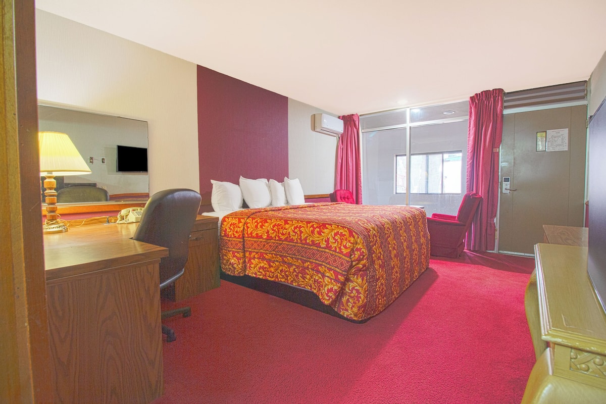 A hotel room with a bed, desk, chair, and a television.