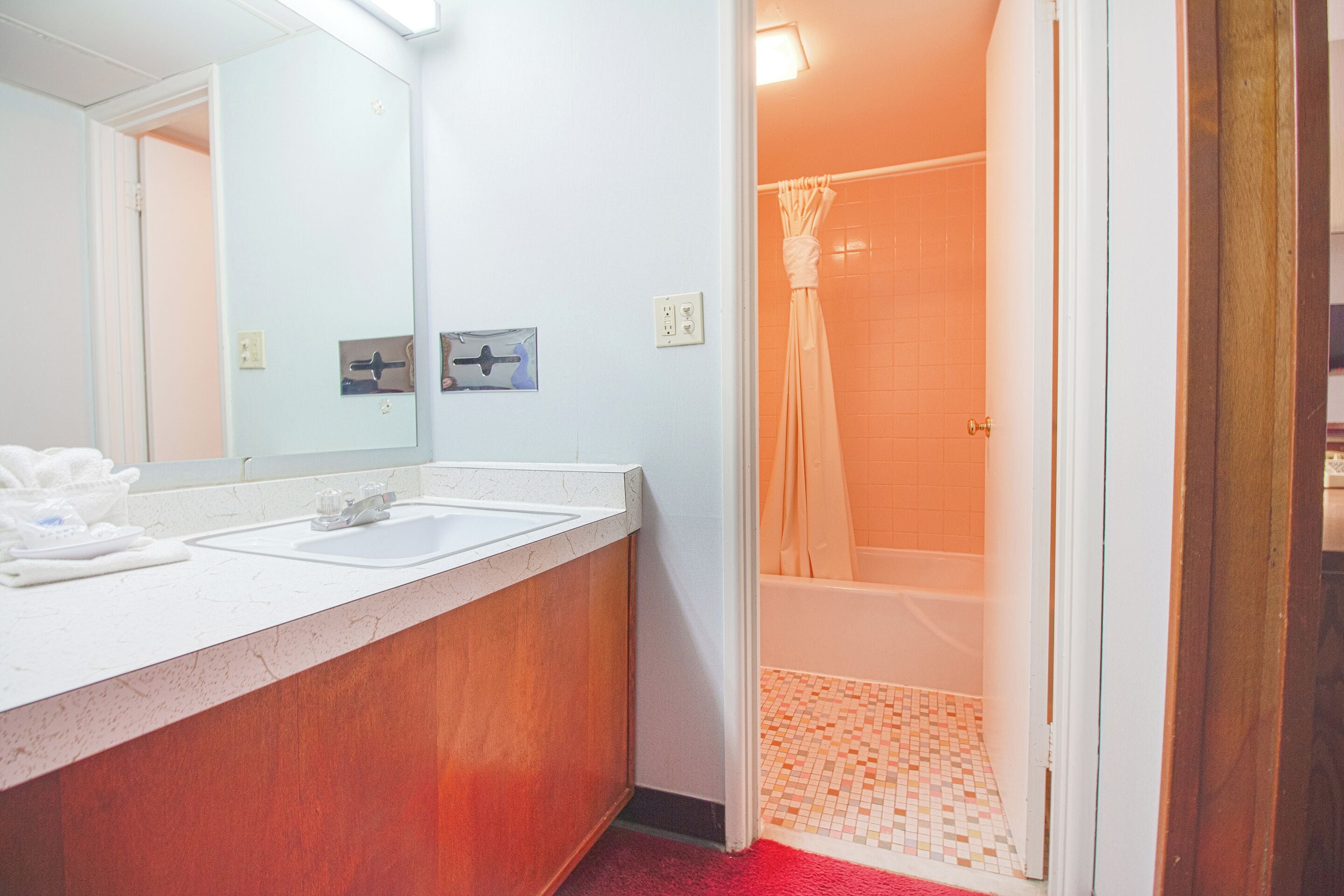 A bathroom with a white sink, a mirror, and a shower area with a tiled floor.