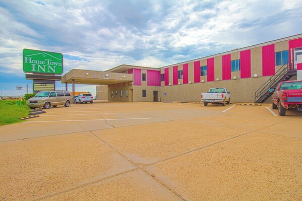 A HomeTown Inn with a parking lot, a covered walkway, and a building with pink and beige exterior walls.