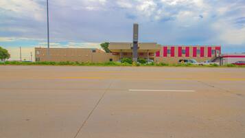 A building with a flat roof, a central vertical structure, and a parking lot in front.