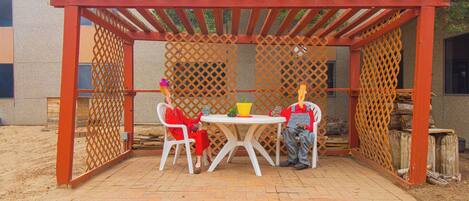 A covered patio area with a table and chairs, a wooden pergola, and a lattice screen.