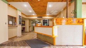 A hotel lobby with a wooden ceiling, a reception desk, a black mat, and a tiled floor. - HomeTown Inn by OYO - Liberal, KS (Liberal)