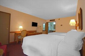 A hotel room with a bed, a desk with a chair, a television, and a mirror.