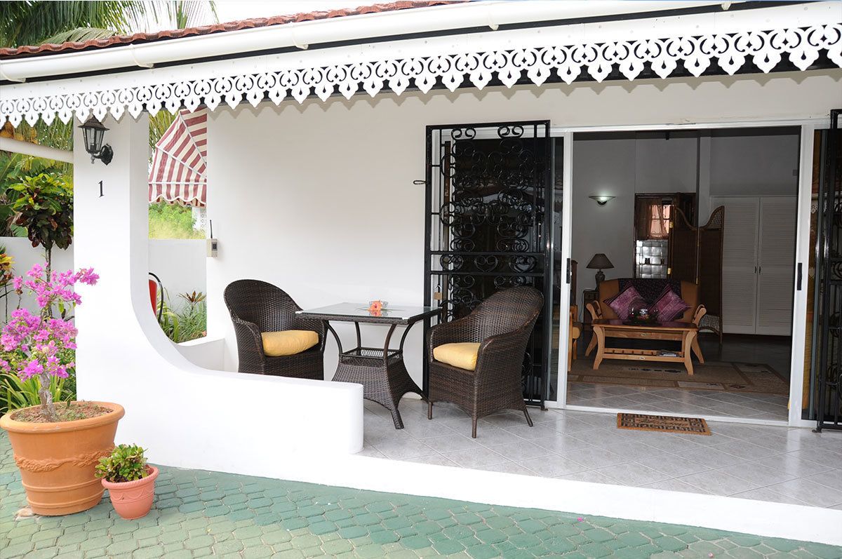 A covered outdoor seating area with wicker furniture and potted plants.