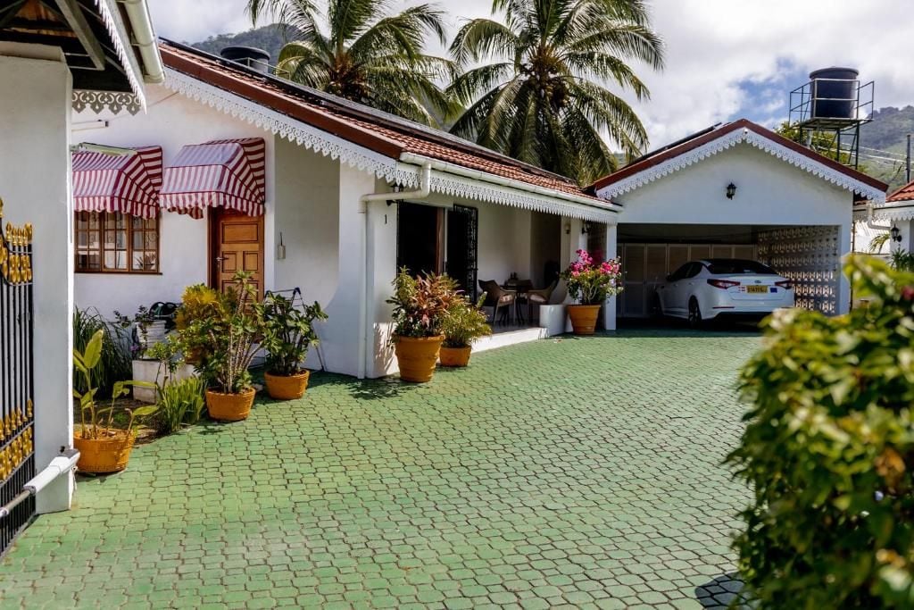 Una propiedad residencial con entrada pavimentada, porche cubierto, garaje y plantas en macetas.