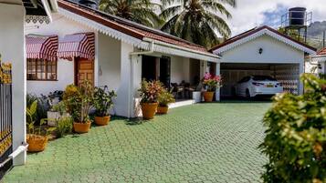 Una propiedad residencial con entrada pavimentada, porche cubierto, garaje y plantas en macetas.
