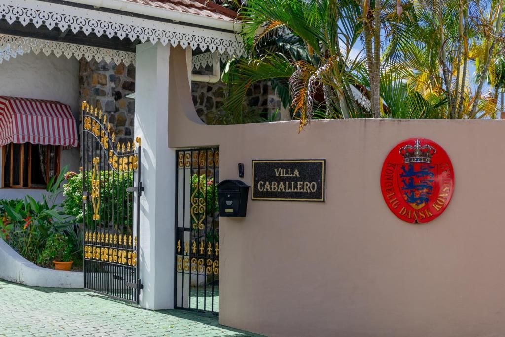 Une entrée fermée par un portail, sur laquelle on peut lire l’inscription « Villa Caballero », et où figurent des armoiries.