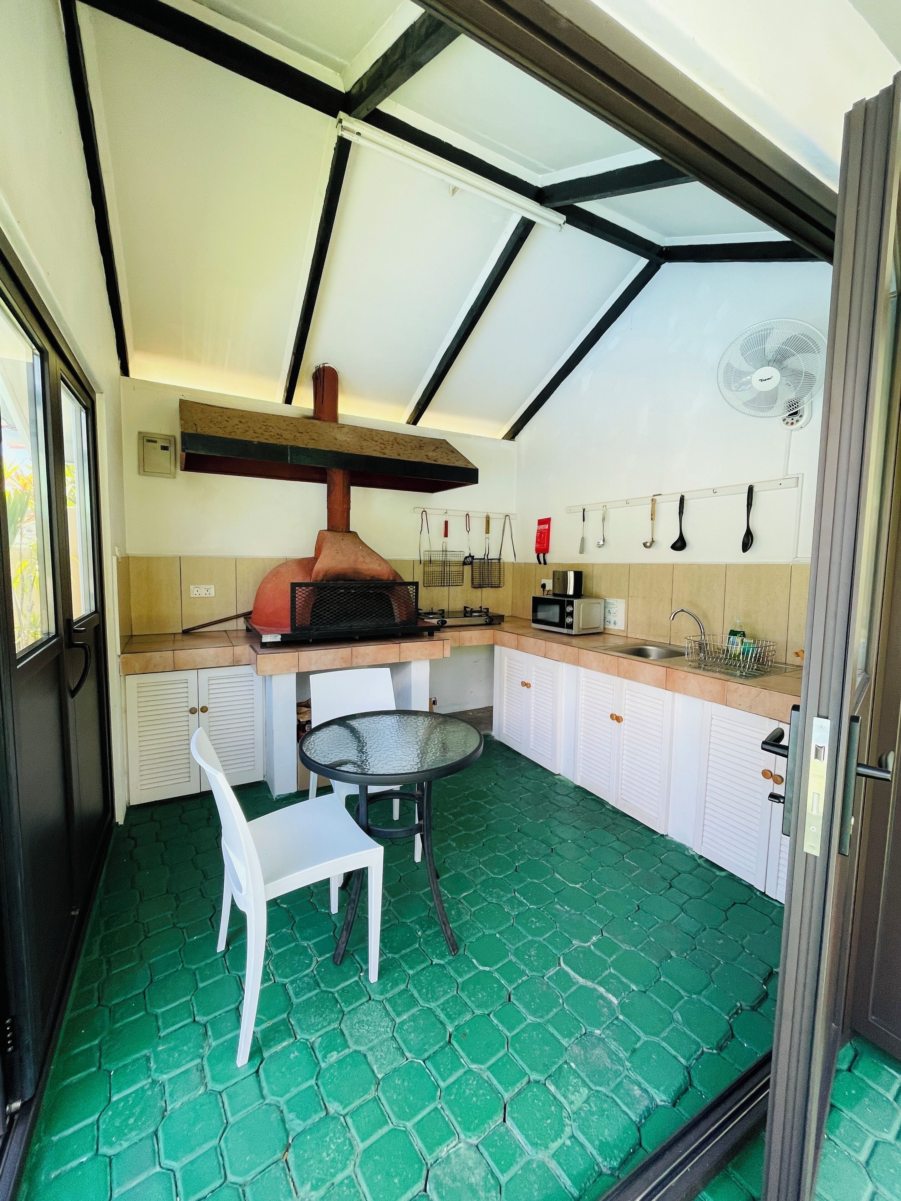 A compact kitchen with a built-in oven, a dining table, and a fan.