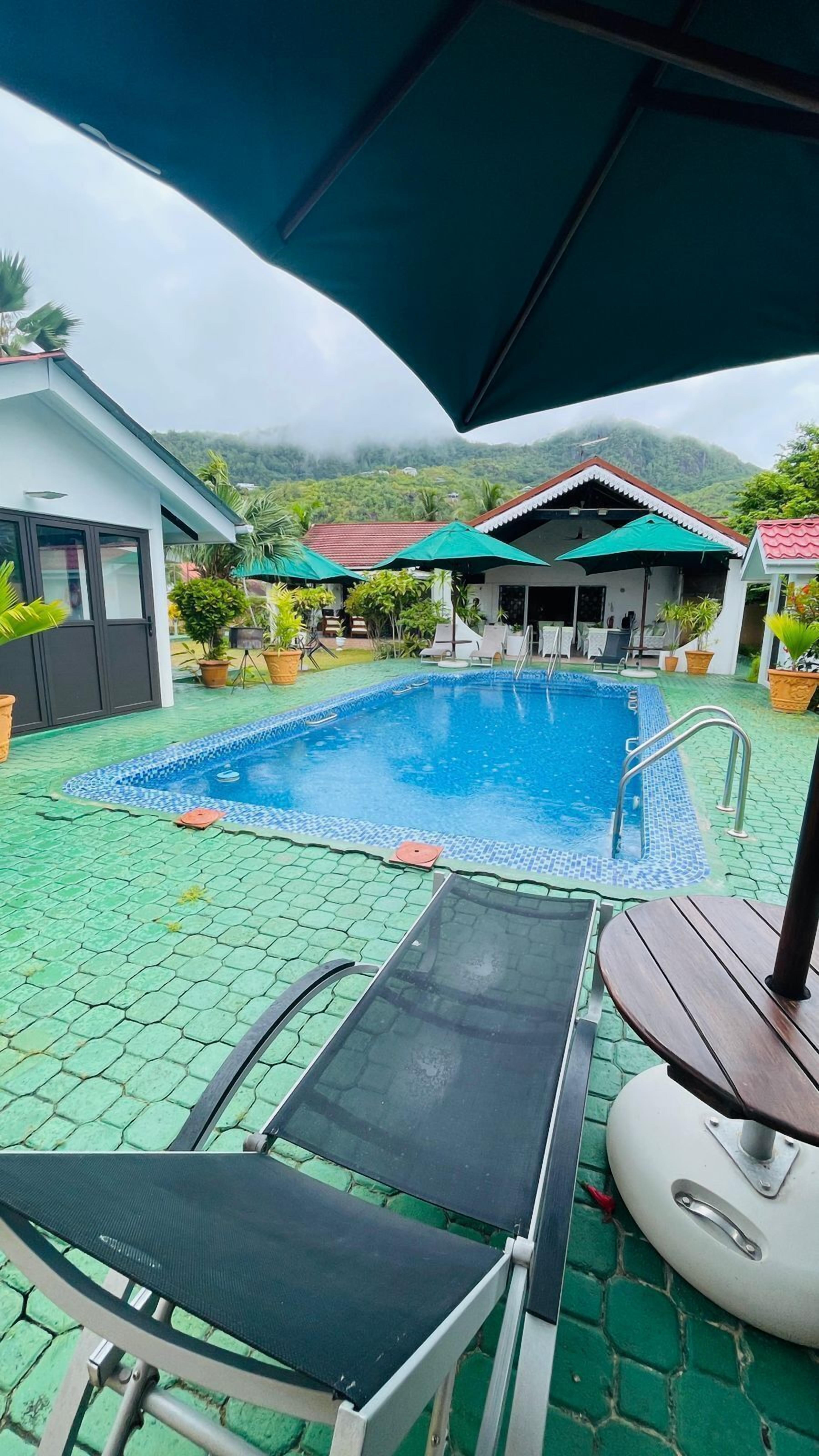 Una piscina al aire libre, sombrillas, sillones reclinables de piscina