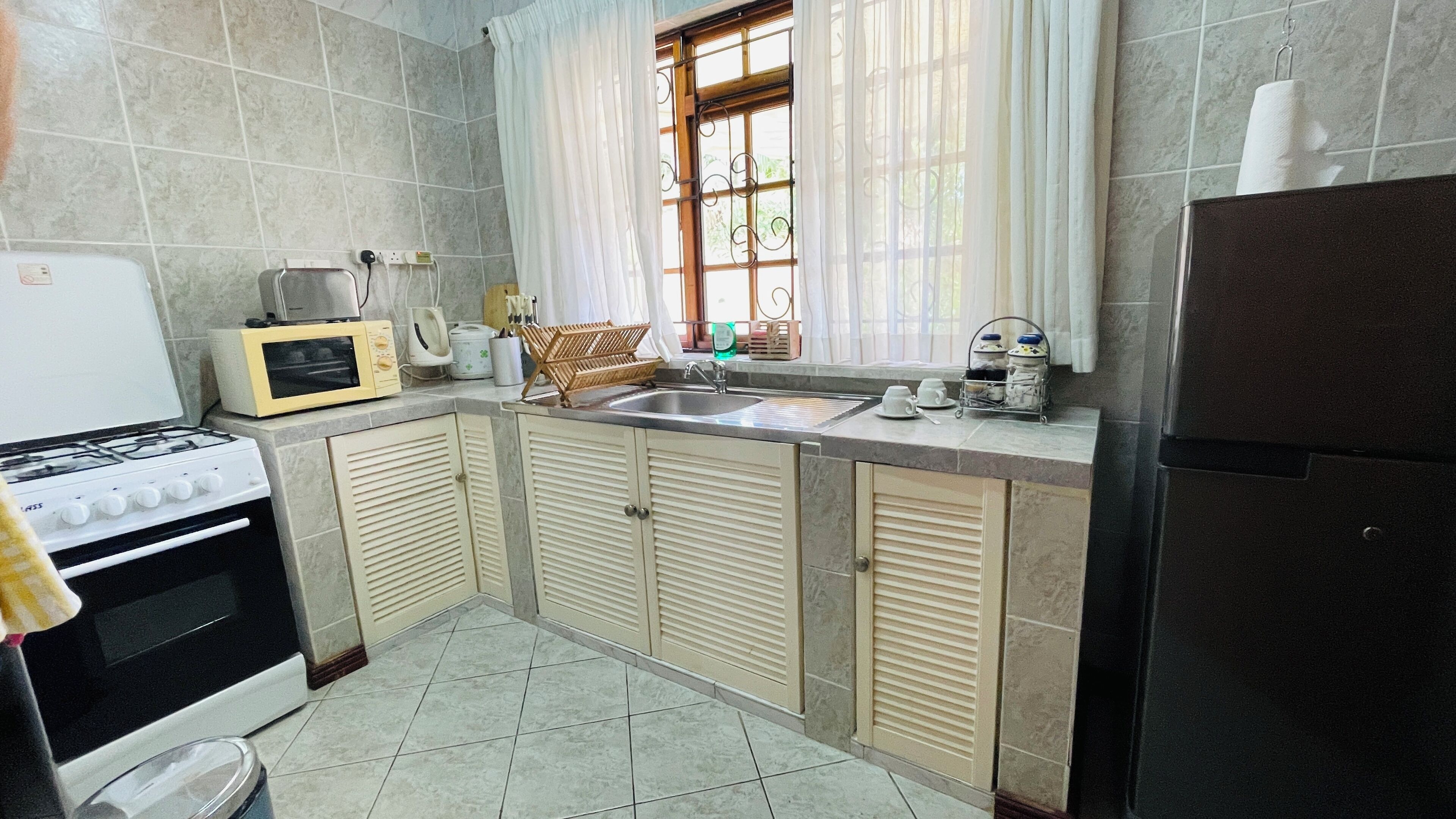 Cocina compacta con estufa a gas, microondas, lavaplatos y refrigerador.