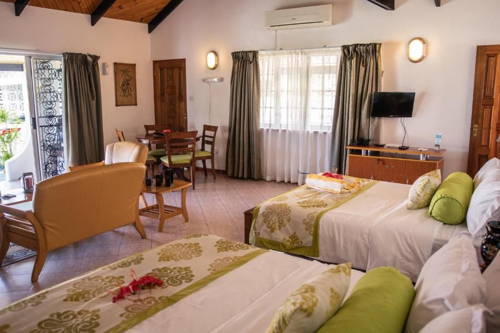 A hotel room with two beds, a desk with a chair, a television, and a window with curtains.
