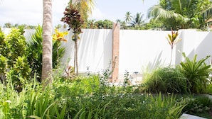 Een weelderige tuin met diverse planten en een witte muur op de achtergrond.