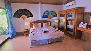 Un dormitorio amplio con una cama grande, un armario y un ventilador en la pared.