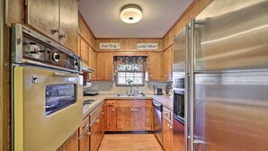 Una cocina con gabinetes de madera, un refrigerador de acero inoxidable, un horno y un lavamanos.