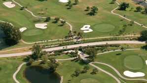 Vista aérea de un campo de golf con múltiples búnkeres, un puente y una masa de agua.