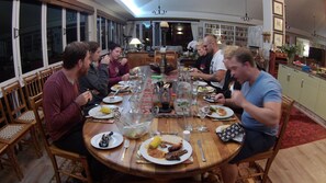 A dining area with a large wooden table set for a meal, surrounded by wooden chairs. - Hillscapes (Port Alfred)