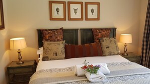 Un lit bien fait, agrémenté d’oreillers à motifs, un mur décoratif orné d’œuvres d’art encadrées et deux lampes de chevet.
