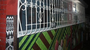A train carriage with ornate metal bars and a mural on the side. - J's Backpackers Hostel (Davao)