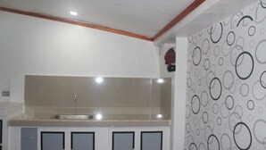 A kitchen with a sink, cabinets, and a patterned wall. - J's Backpackers Hostel (Davao)