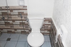 A small bathroom with a toilet, shower, and a towel rack. - J's Backpackers Hostel (Davao)