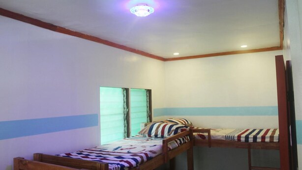 A room with two bunk beds, a ceiling light, and a window with blinds. - J's Backpackers Hostel (Davao)