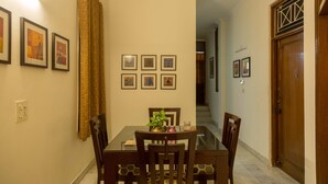 Un coin repas avec une table en verre, des chaises en bois et des tableaux encadrés accrochés au mur.