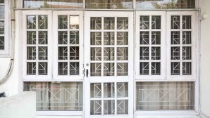 Une façade d’immeuble avec de nombreuses fenêtres, chacune divisée en petits carreaux, et une porte avec un panneau de verre.