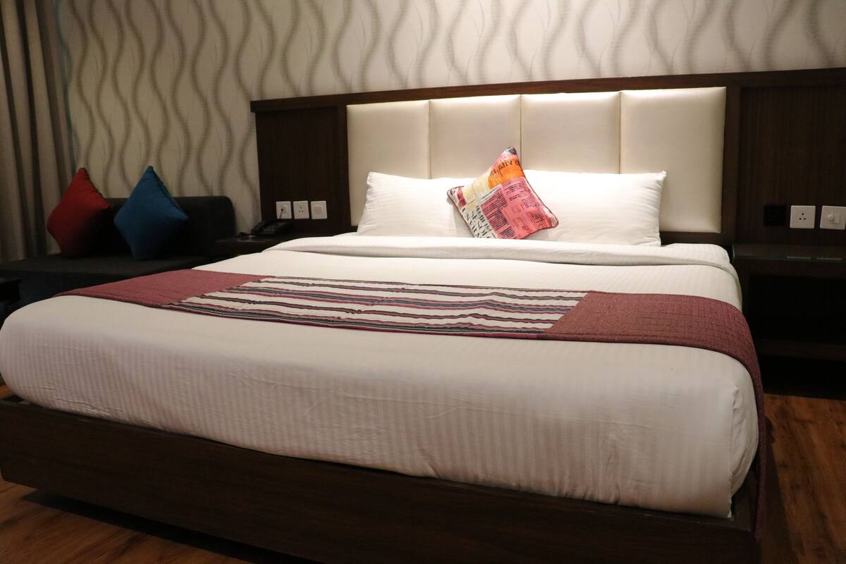 Habitació d'hotel amb un llit gran, una vetusta, una làmpada i un mur amb dibuixos.