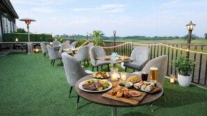 An outdoor dining area with tables and chairs, a variety of dishes, drinks, and candles.