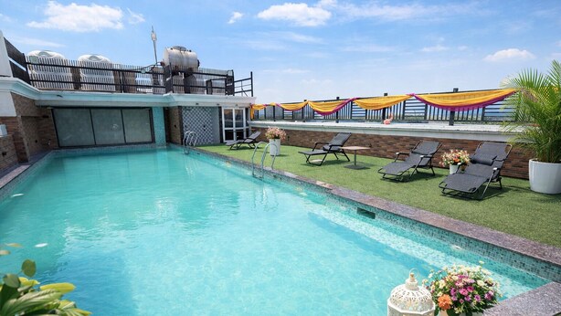 A swimming pool with a clear blue water, surrounded by lounge chairs and a small garden area with potted plants.