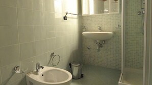 Een badkamer met houten plafond, een toiletbrons, wastafel en douche.