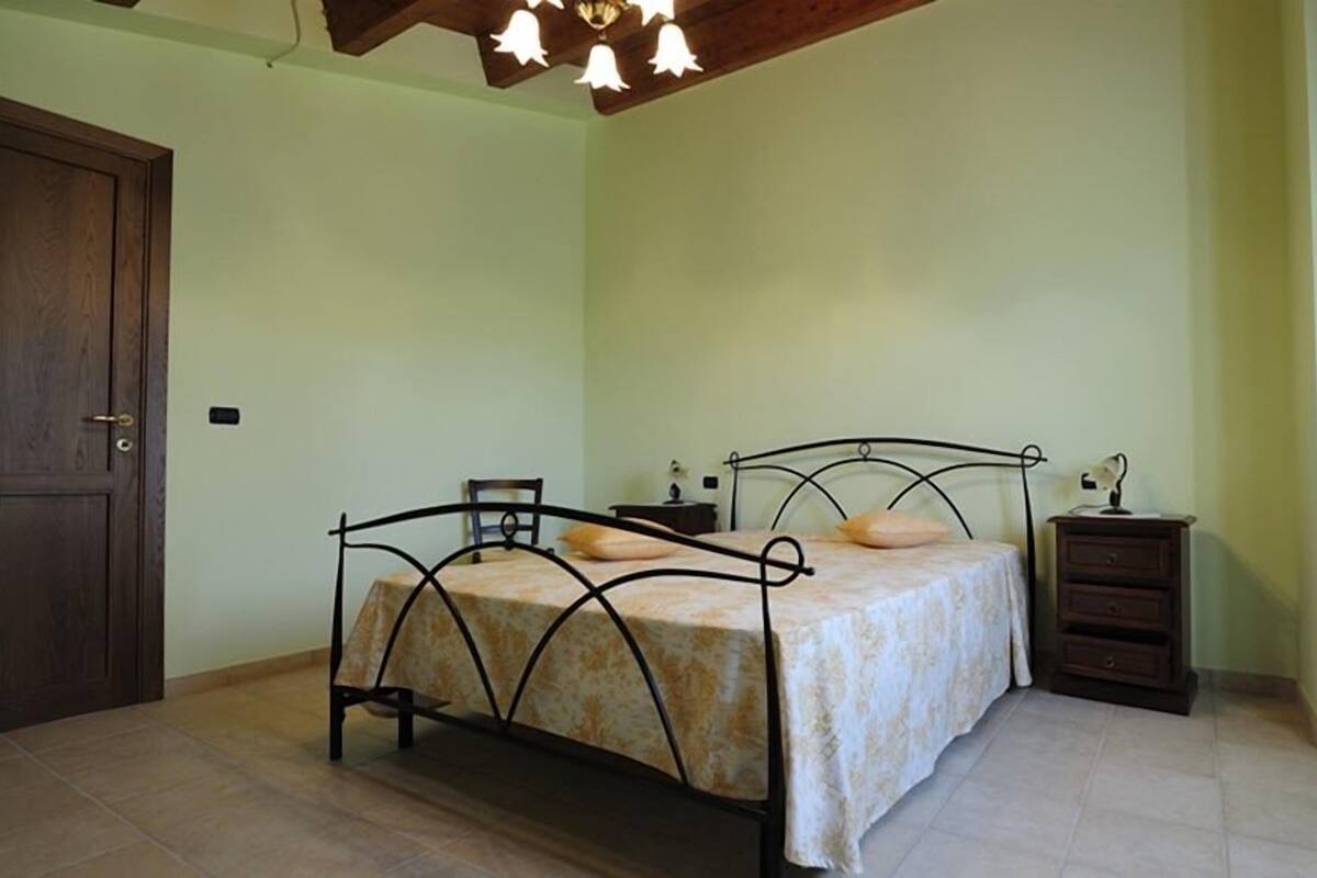 Une chambre à coucher avec un lit, une table de chevet, une commode et une porte en bois.