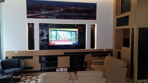 Un salon moderne doté d’un grand téléviseur à écran plat fixé sur un mur en bois, d’un canapé, d’une table basse et d’un tapis à motifs.