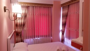 Une chambre d’hôtel avec un lit, une table de chevet, une lampe et des rideaux.