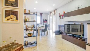A modern kitchen with a dining area, a TV, and a shelf with kitchen items. - 3 bedroom nice apartment in Bari (Bari)
