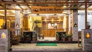 The entrance of Hotel Lake Shore Pōkhara with a reception desk, potted plants, and a green mat. - Hotel Lake Shore (Pokhara)