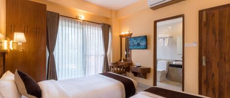 Habitación de hotel con dos camas, un escritorio, un espejo y un equipo de aire acondicionado.