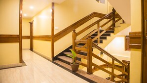A hotel hallway with a wooden staircase, a potted plant, and a marble floor. - Hotel Lake Shore (Pokhara)