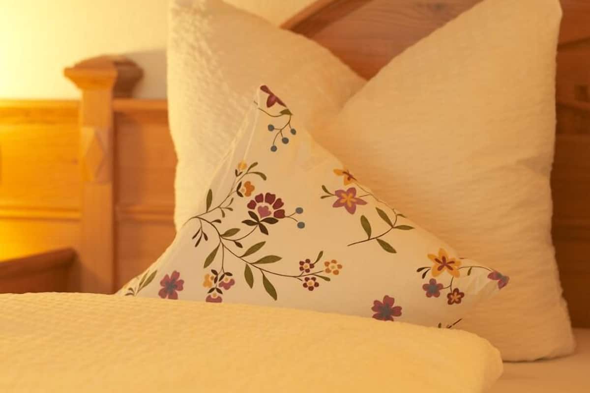 Un lit avec deux oreillers, dont un uni et l’autre à motifs floraux.