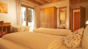 Un dormitorio con dos camas, un armario de madera, un espejo y una ventana con cortinas.