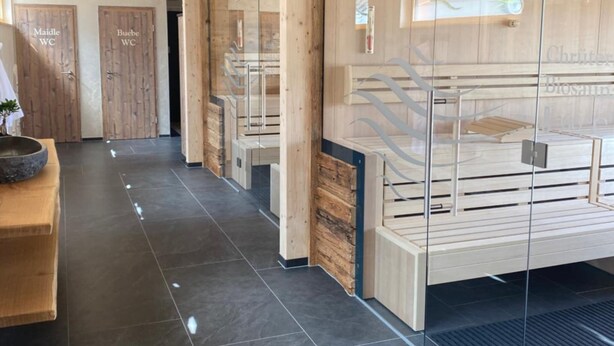 Un pasillo moderno de hotel con paredes de madera, divisiones de vidrio y piso de baldosas.