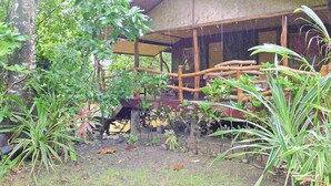 A rustic wooden building with a thatched roof, surrounded by lush greenery and trees. - Dabdab Tourist Inn (Puerto Princesa)