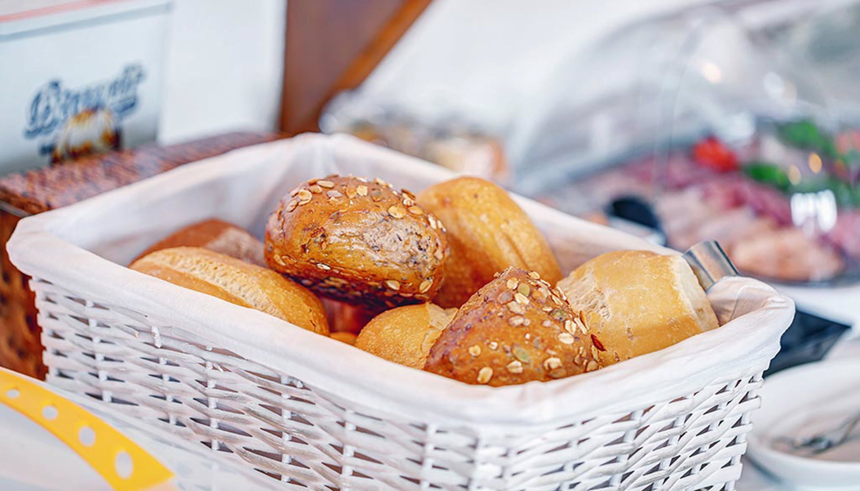 Ein Korb mit verschiedenen Brotsorten und Gebäck, darunter Brötchen und Hefeknödel mit Saaten.