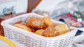 Ein Korb mit verschiedenen Brotsorten und Gebäck, darunter Brötchen und Hefeknödel mit Saaten.