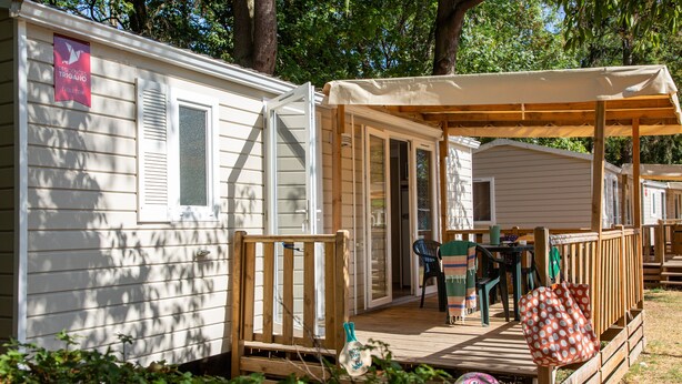 Une maison mobile avec une véranda, une table et des chaises.