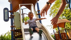 Un enfant qui descend en glissant sur un toboggan d’aire de jeux.