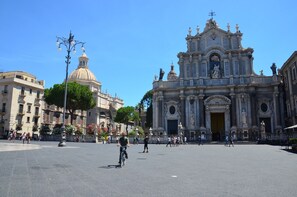 A plaza with a large historic building featuring ornate architecture and a dome. - Tre Stelle al Duomo (Catania)