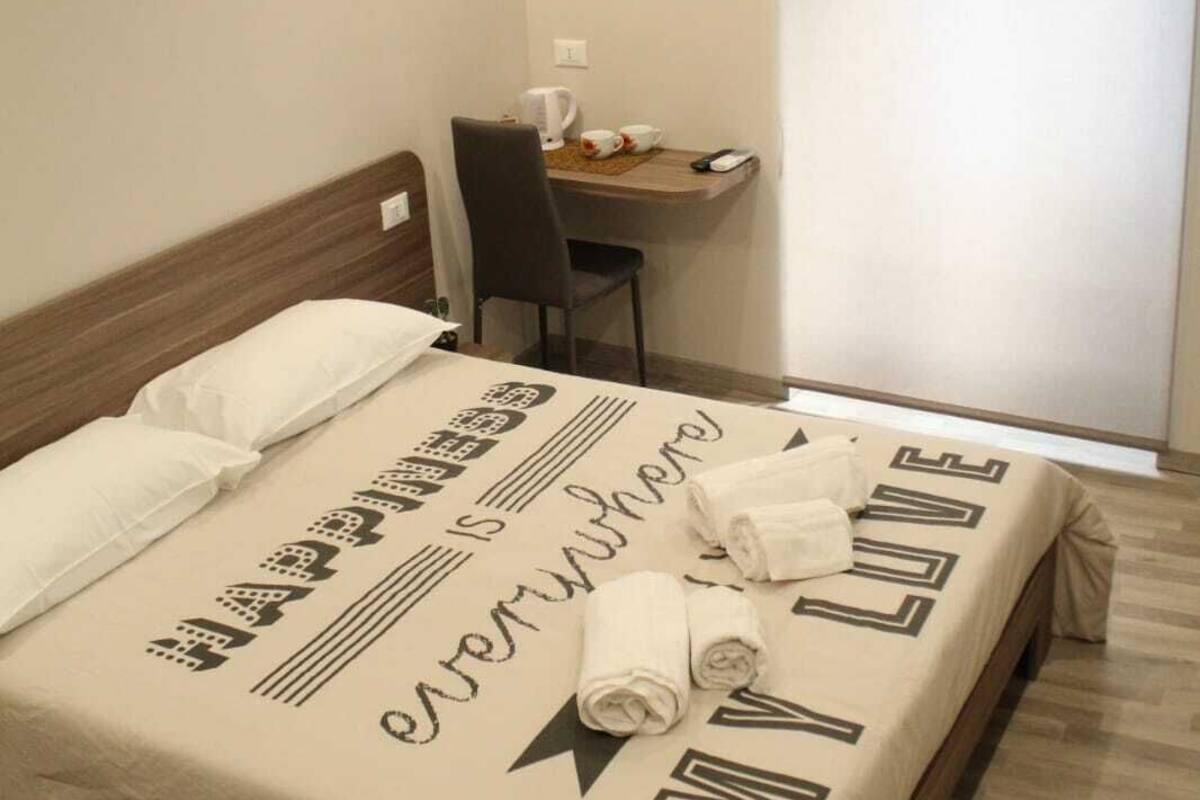 A hotel room with a bed, a desk, and a chair.